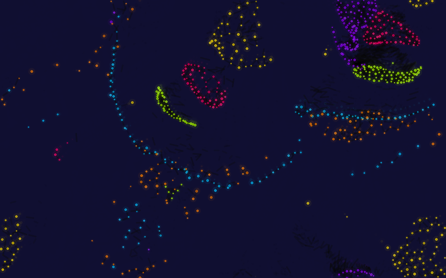 Particle Life: clusters de partículas de colores sobre fondo azul noche