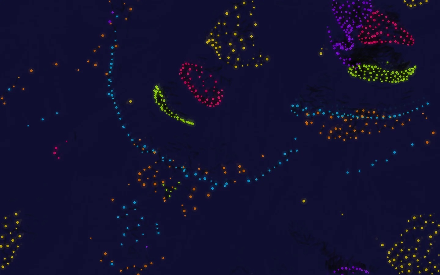 Particle Life: clusters de partículas de colores sobre fondo azul noche